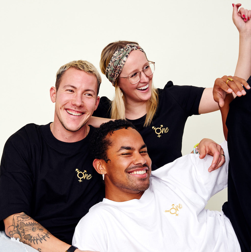 Drei Personen tragen Shirts von BeeProud, lächeln und haben Spaß