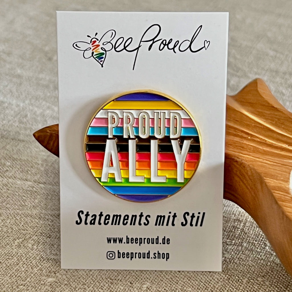 Runde Anstecknadel in Regenbogenfarben mit der Aufschrift Proud Ally
