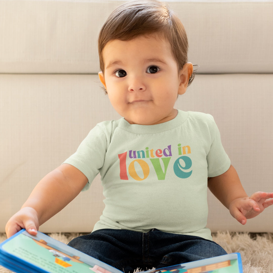 Baby trägt Shirt in der Farbe Lime mit buntem Aufdruck united in love