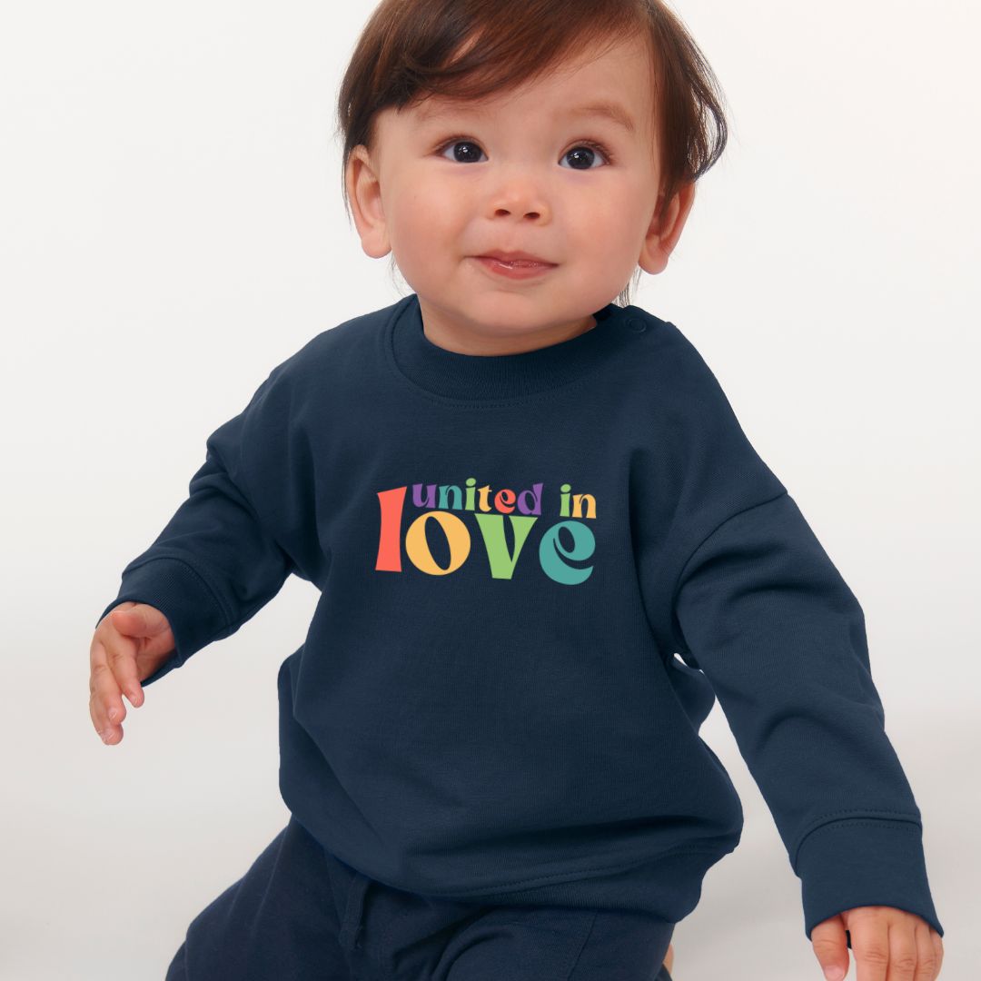 Baby trägt dunkelblaues Sweatshirt mit buntem Aufdruck united in love