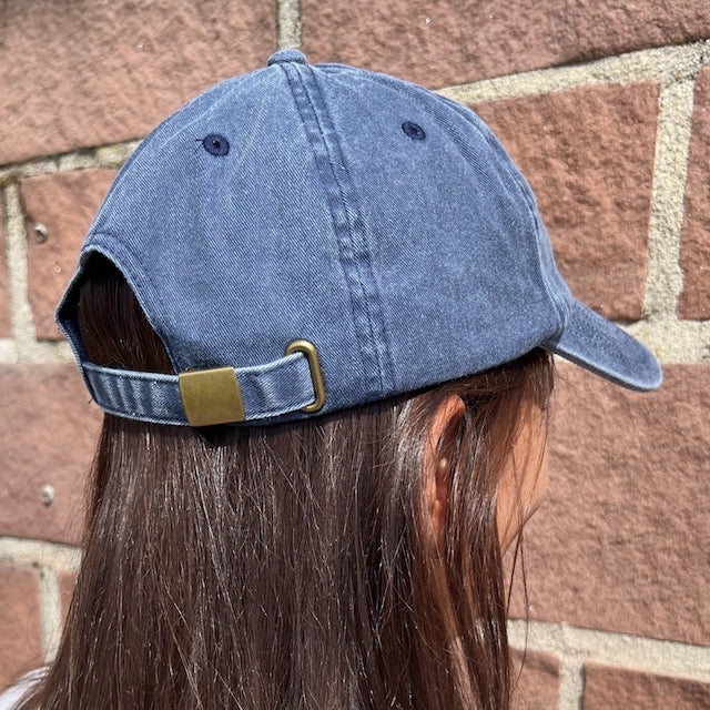 Model trägt Vintage Cap in blau mit Metallverschluss von hinten