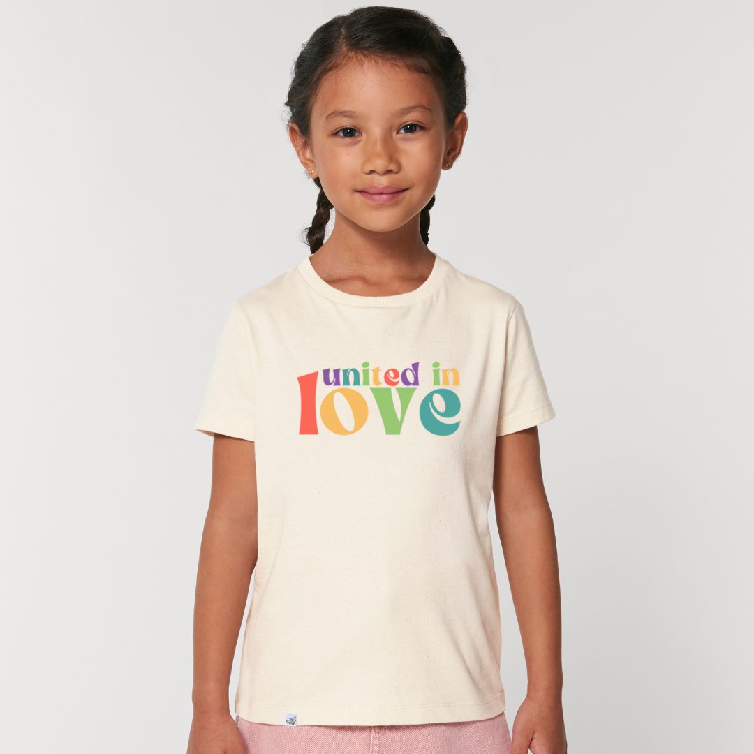 Kind lächelt und trägt naturfarbenes Shirt mit buntem Aufdruck united in love