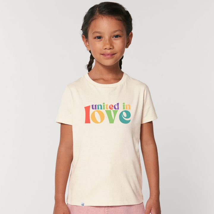 Kind lächelt und trägt naturfarbenes Shirt mit buntem Aufdruck united in love