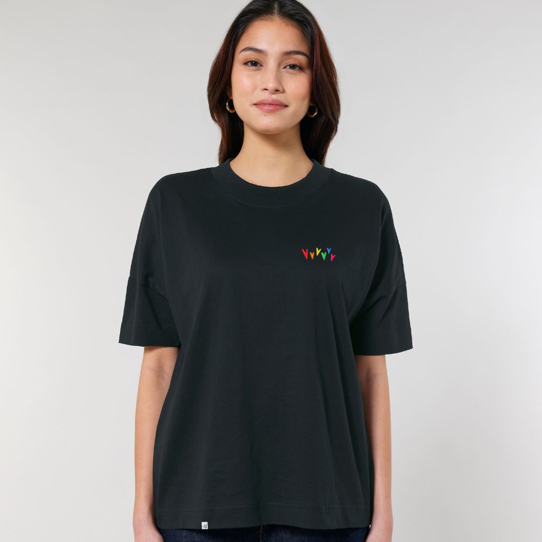 Model trägt oversized Shirt Regenbogenherzen Stick in der Farbe Schwarz..