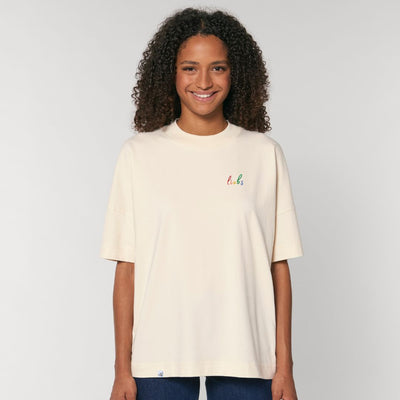 Model trägt oversized Shirt mit dem Stickdesign liebs auf der Brust in der Farbe Natur.