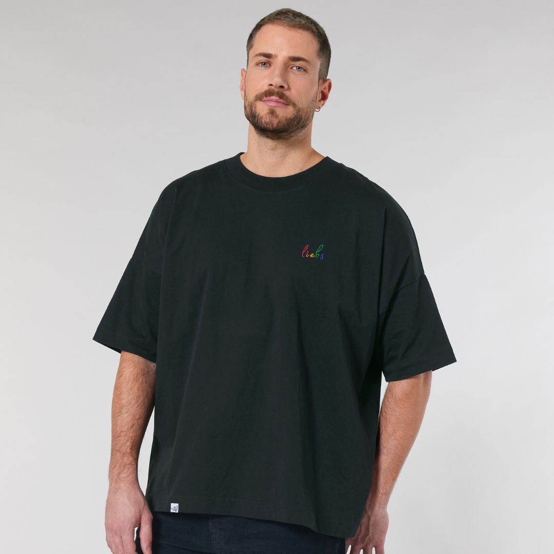 Model trägt oversized Shirt mit dem Stickdesign liebs auf der Brust in der Farbe Schwarz.