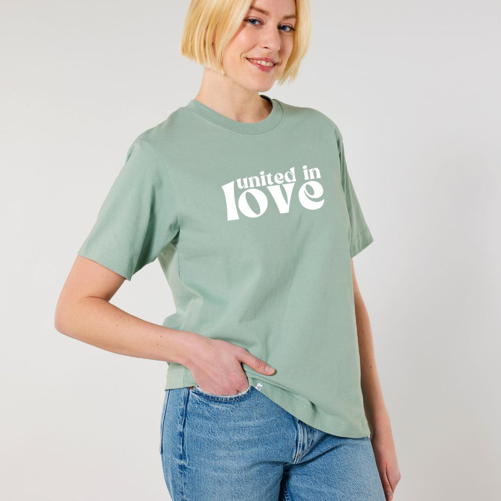 Model lächelt und trägt oversized Shirt in der Farbe Aloe mit dem Aufdruck united in love