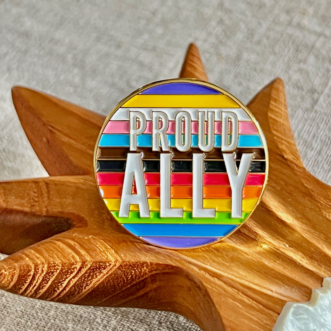 Runde Anstecknadel in Regenbogenfarben mit der Aufschrift Proud Ally