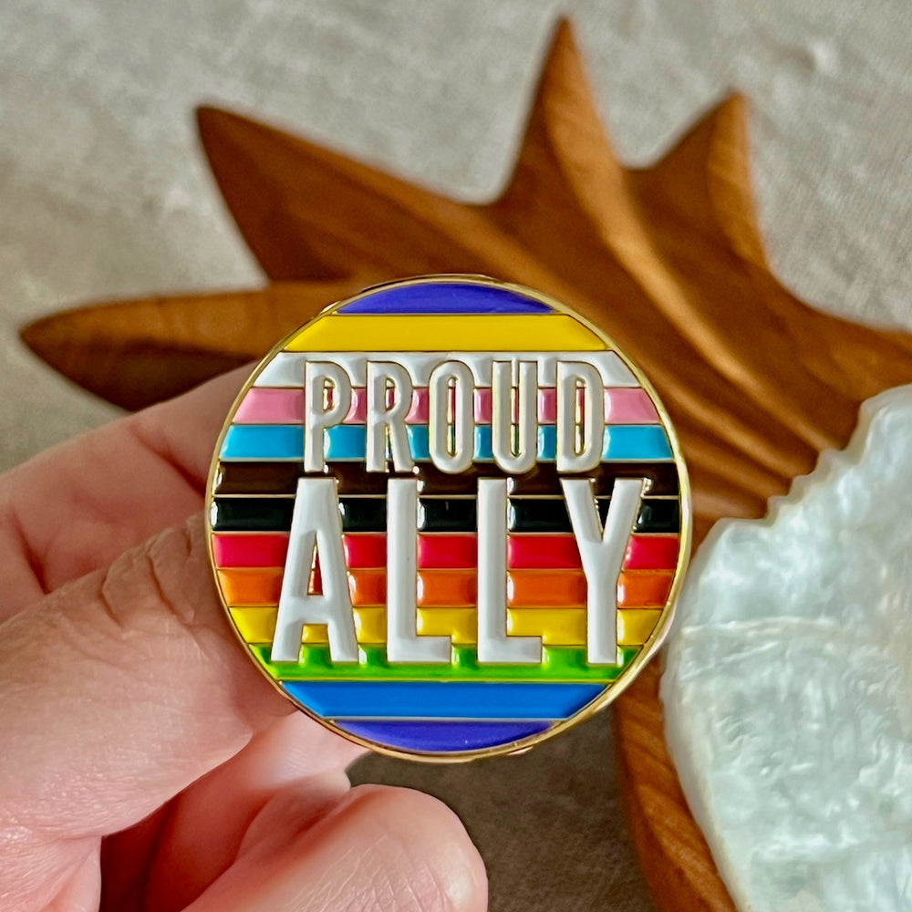 Runde Anstecknadel in Regenbogenfarben mit der Aufschrift Proud Ally