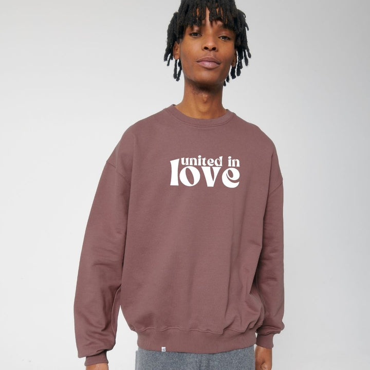 Model lächelt und trägt Sweatshirt in der Farbe Aubergine mit dem Aufdruck united in love