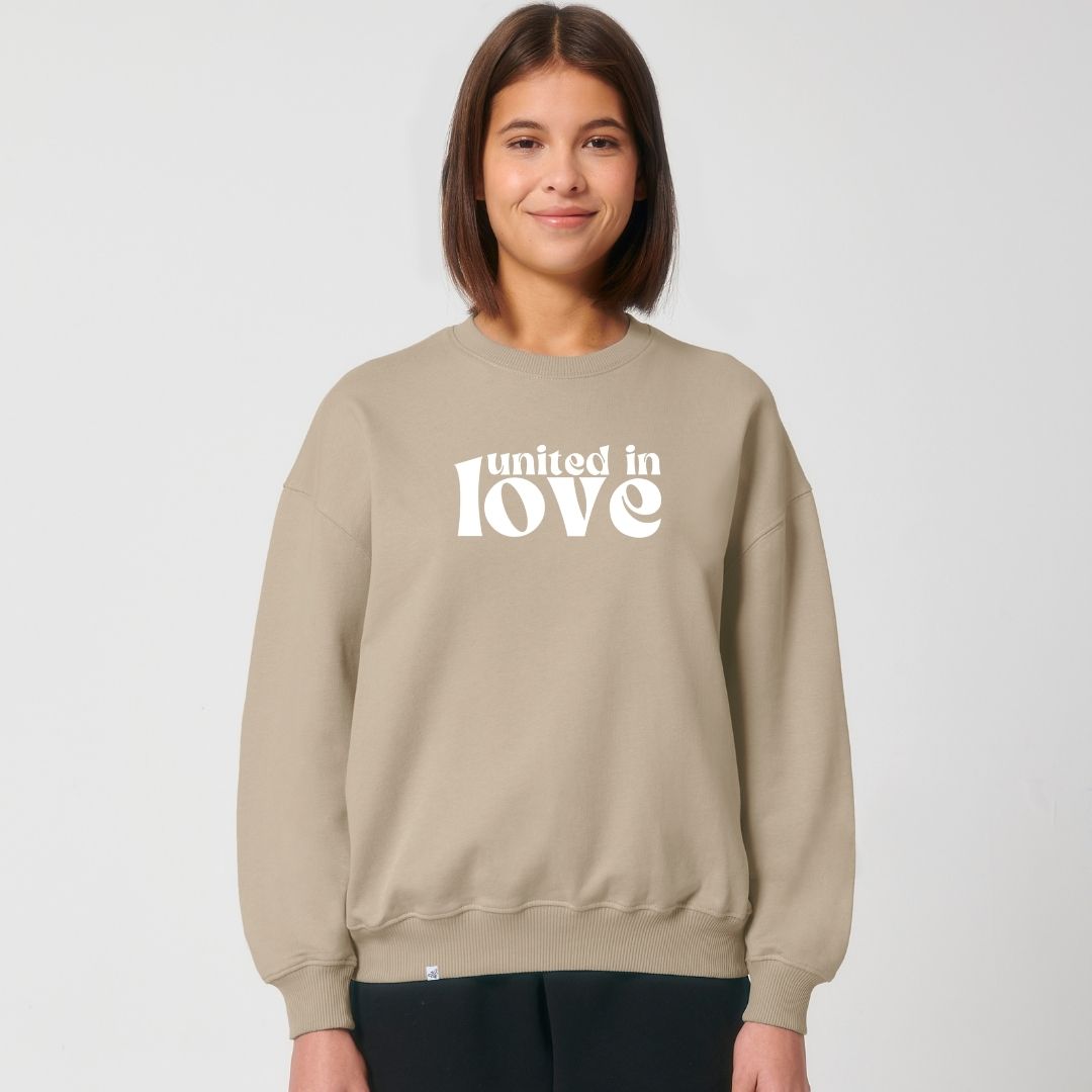 Model lächelt und trägt Sweatshirt in der Farbe Desert mit dem Aufdruck united in love
