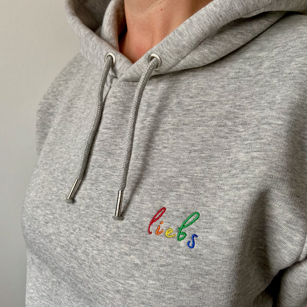 Nahaufnahme des Sticks liebs in Regenbogenfarben auf einem hellgrau melierten Hoodie