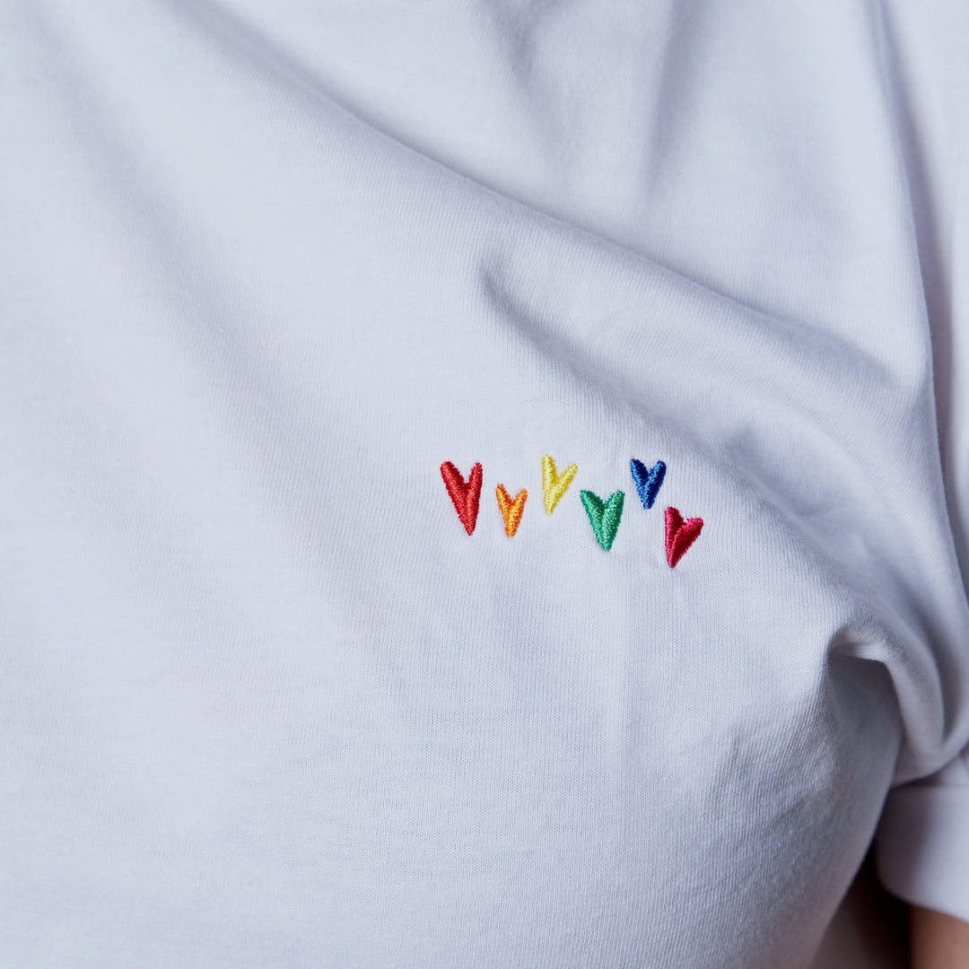 Nahaufnahme weißes Shirt mit bunten Regenbogenherzen in Stick auf der Brust