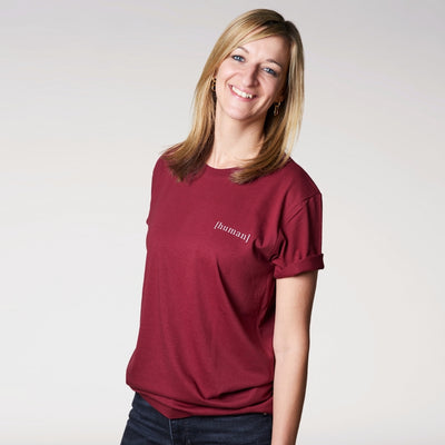 Model trägt burgundyfarbenes Shirt mit kleiner Aufschrift human auf der Brust