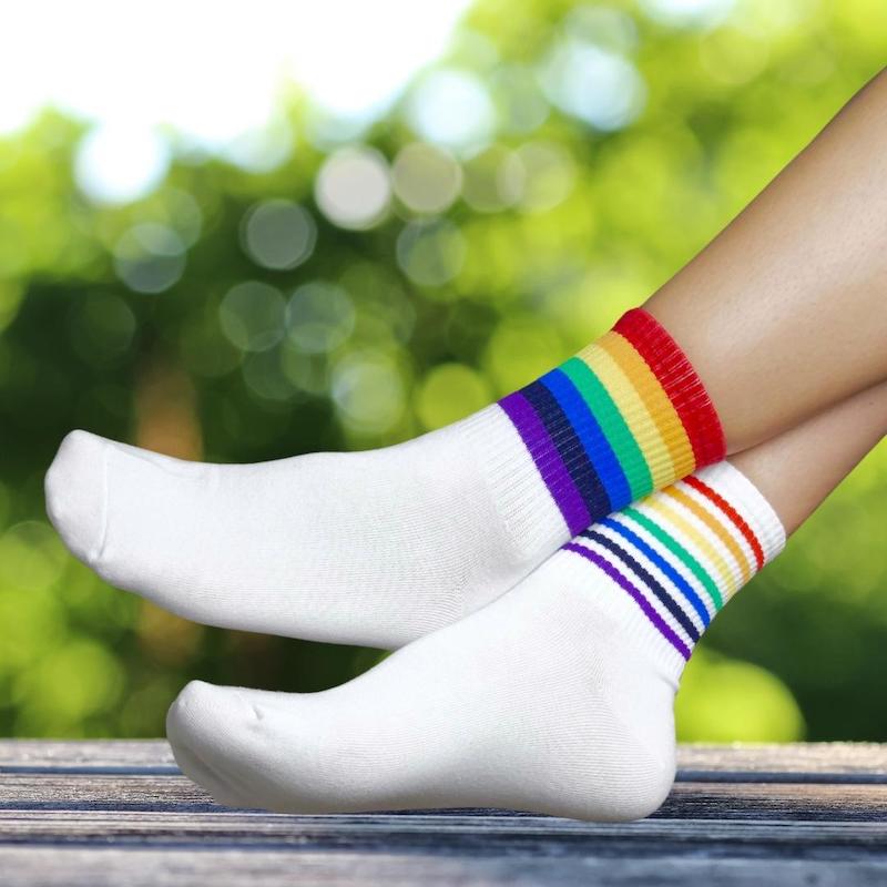 Nahaufnahme von zwei Füßen, die Socken mit Streifen in Regenbogenfarben tragen