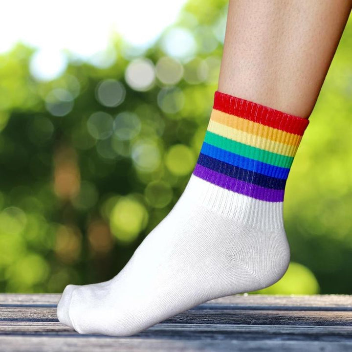 Nahaufnahme eines Fußes, der eine Socke mit dicken Streifen in Regenbogenfarben trägt