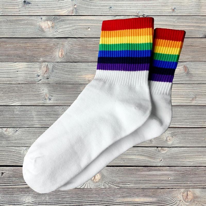 Socken mit dicken Streifen in Regenbogenfarben liegen auf einem Holztisch