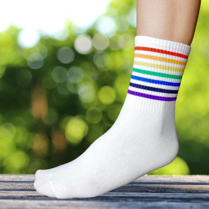 Nahaufnahme eines Fußes, der eine Socke mit dünnen Streifen in Regenbogenfarben trägt