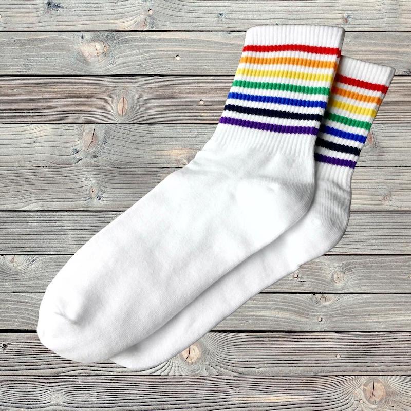 Socken mit dünnen Streifen in Regenbogenfarben liegen auf einem Holztisch