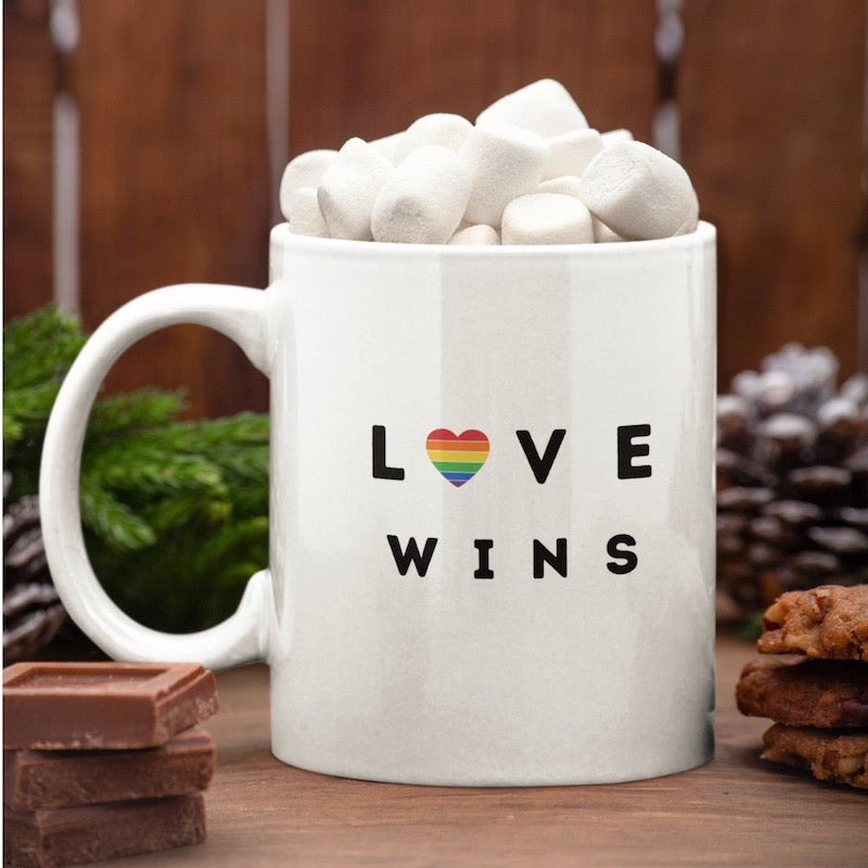 Weiße Tasse mit der Aufschrift Love Wins und einem Regenbogenherz gefüllt mit Marshmallows